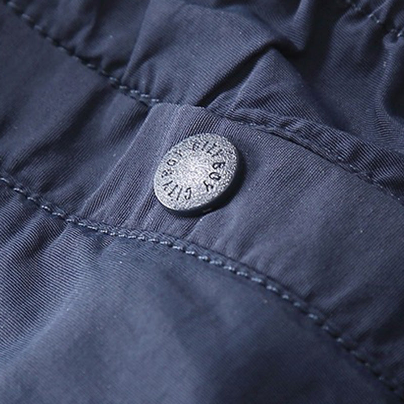 Close-up view of a metal button on the navy Sakura Breeze waterproof breathable casual pants, with 'CITY BOY' text embossed on its surface.