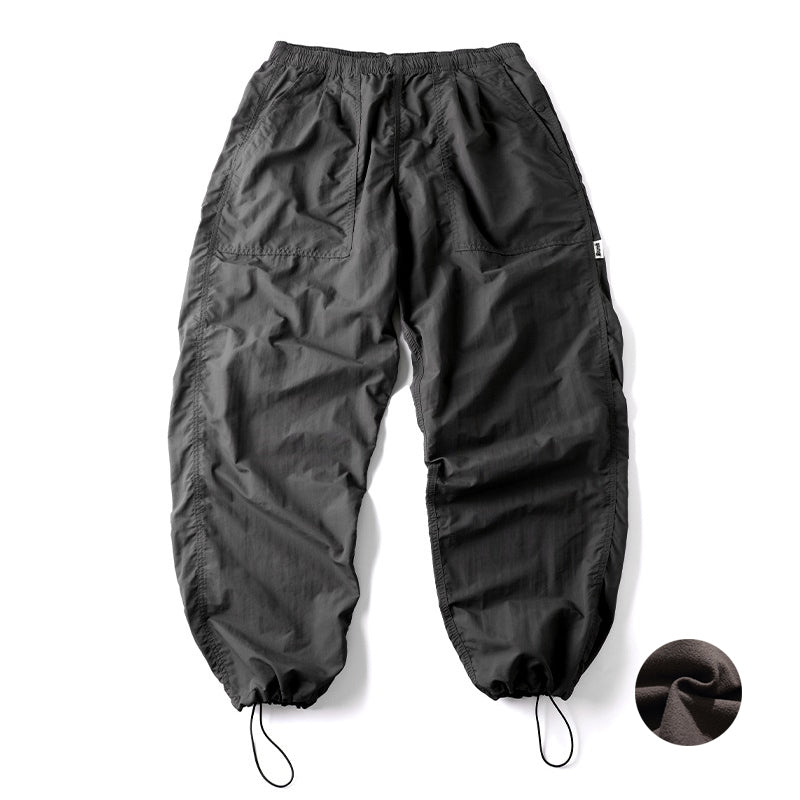 Full back view of the deep grey Sakura Breeze waterproof breathable casual pants, laid flat, with elastic cuffs and a close-up inset showing the soft fleece fabric texture.