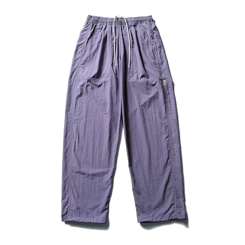 Full front view of the purple Sakura Breeze waterproof breathable casual pants, laid flat, showcasing the relaxed fit and elastic waistband with white drawstring.