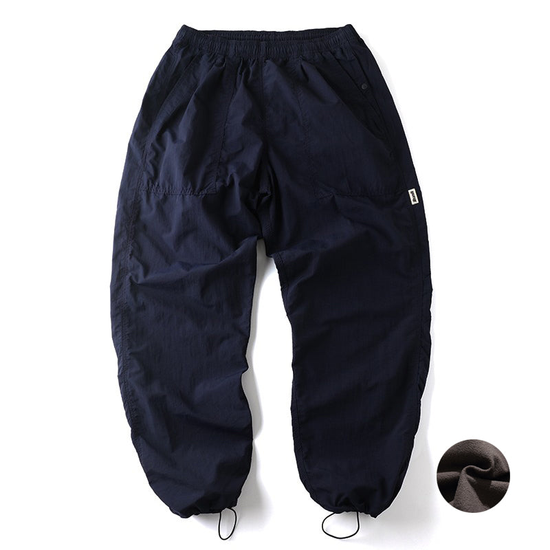 Navy Sakura Breeze waterproof breathable casual pants with a relaxed fit, laid flat showing the front view. A small circular swatch of soft fleece fabric is shown in the bottom right corner, indicating a fleece-lined variant.