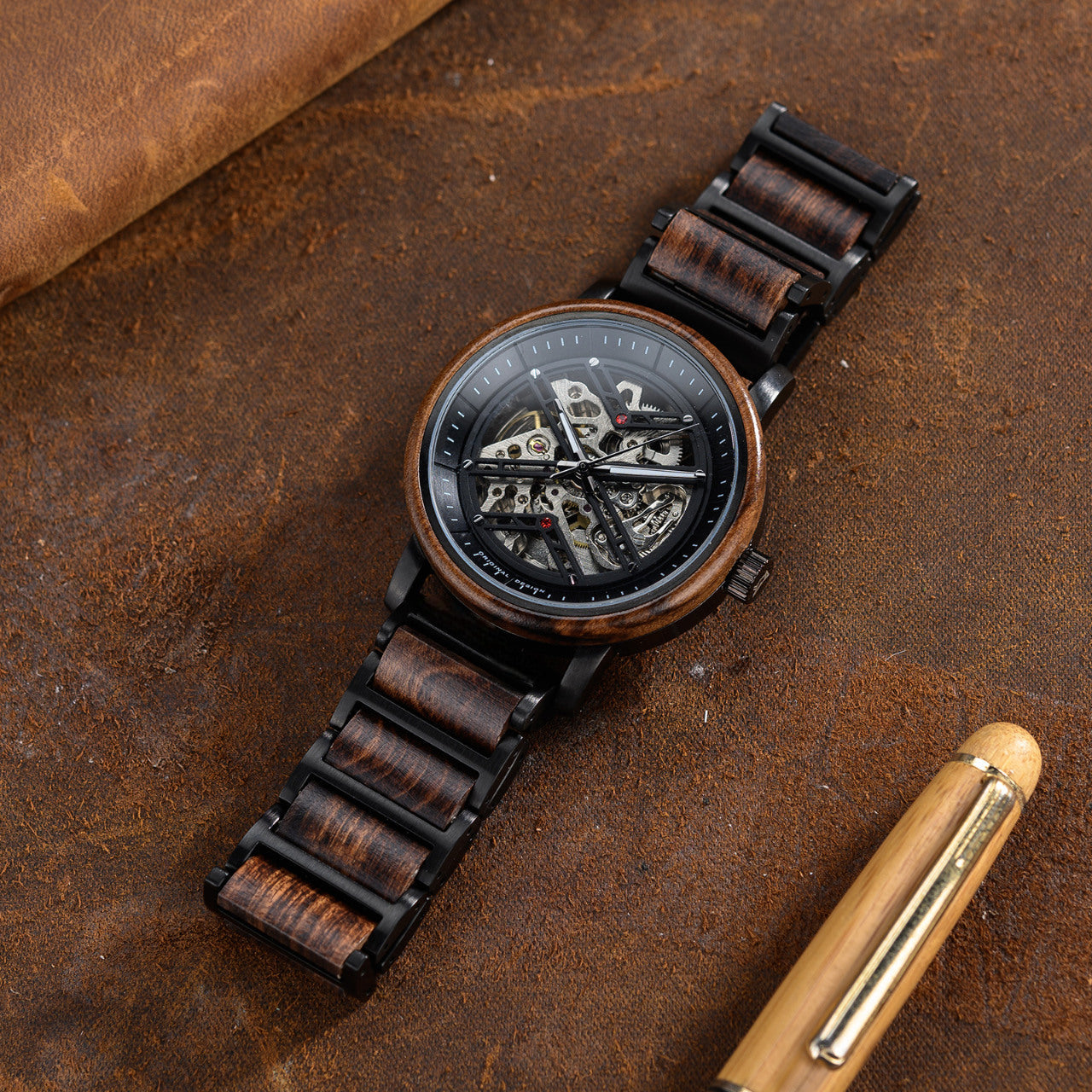 Terra Brown men's wooden watch with natural finish, close-up overhead shot showing the intricate mechanical movement on a brown leather surface.