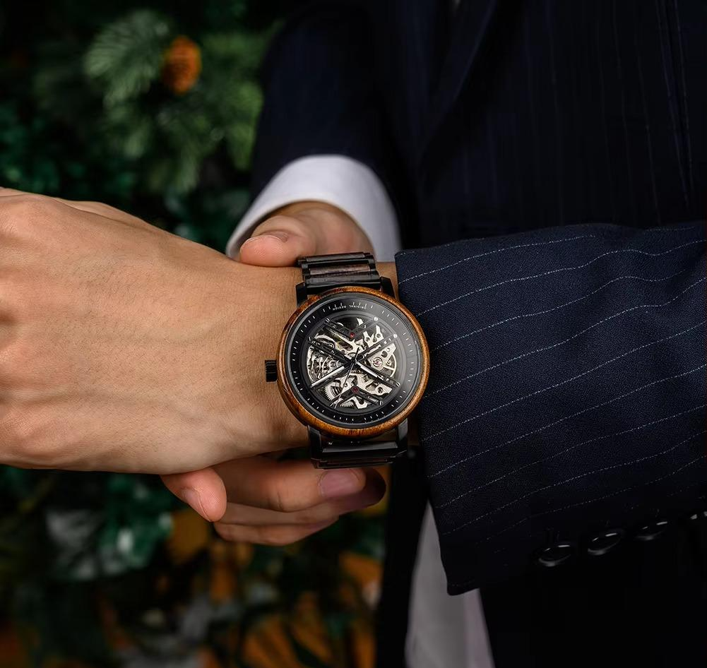 Terra Brown men's wooden watch with natural finish worn on a man's wrist, adjusting the watch while wearing a dark pinstripe suit jacket.