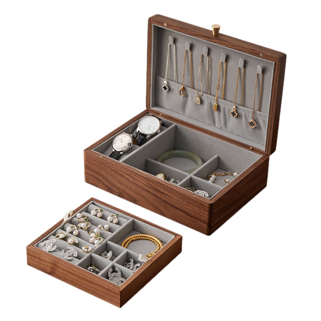 Open solid walnut wood jewelry box with its removable tray pulled out, showcasing various jewelry items like necklaces, watches, rings, and bracelets in grey-lined compartments. Highlights the versatile storage options.