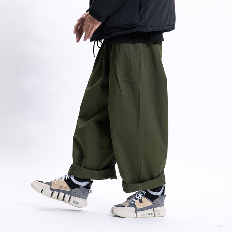 Male model in a walking pose wearing green Urban Luxe wide-leg casual pants made from soft fabric with a relaxed fit, cuffed at the ankles and paired with sneakers.