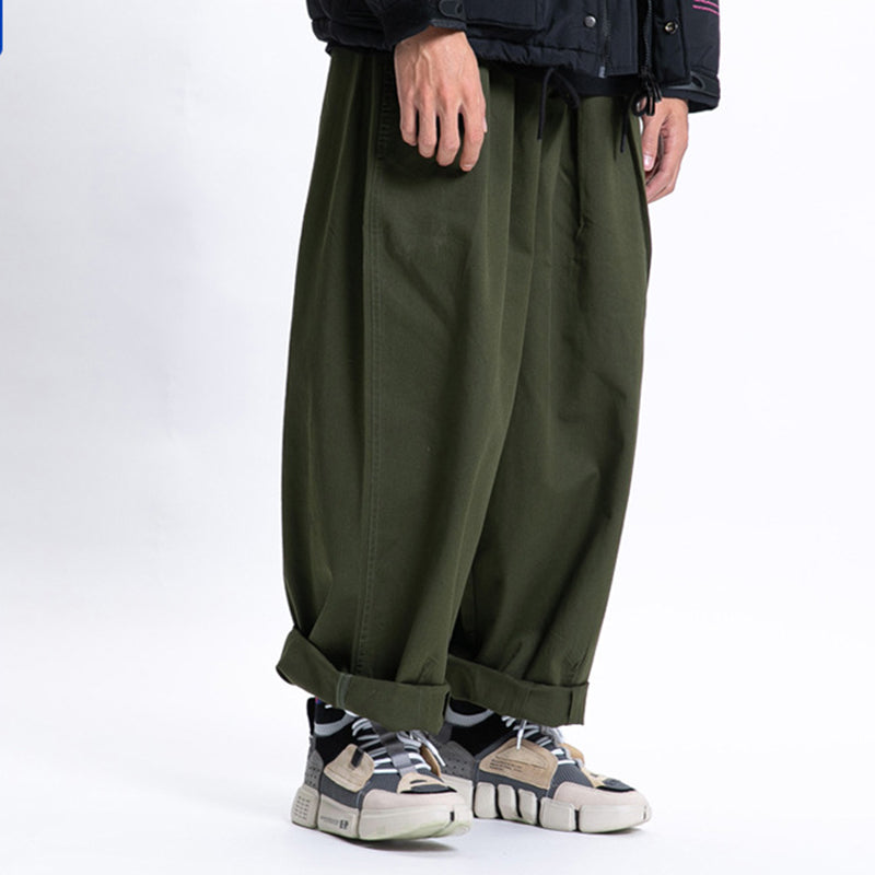 Male model wearing green Urban Luxe wide-leg casual pants made from soft fabric with a relaxed fit, cuffed at the ankles and paired with sneakers.