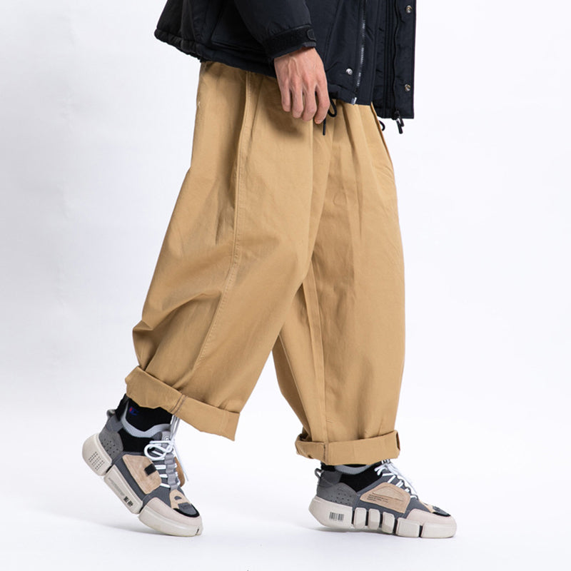 Male model in a walking pose wearing khaki Urban Luxe wide-leg casual pants made from soft fabric with a relaxed fit, cuffed at the ankles and paired with sneakers.