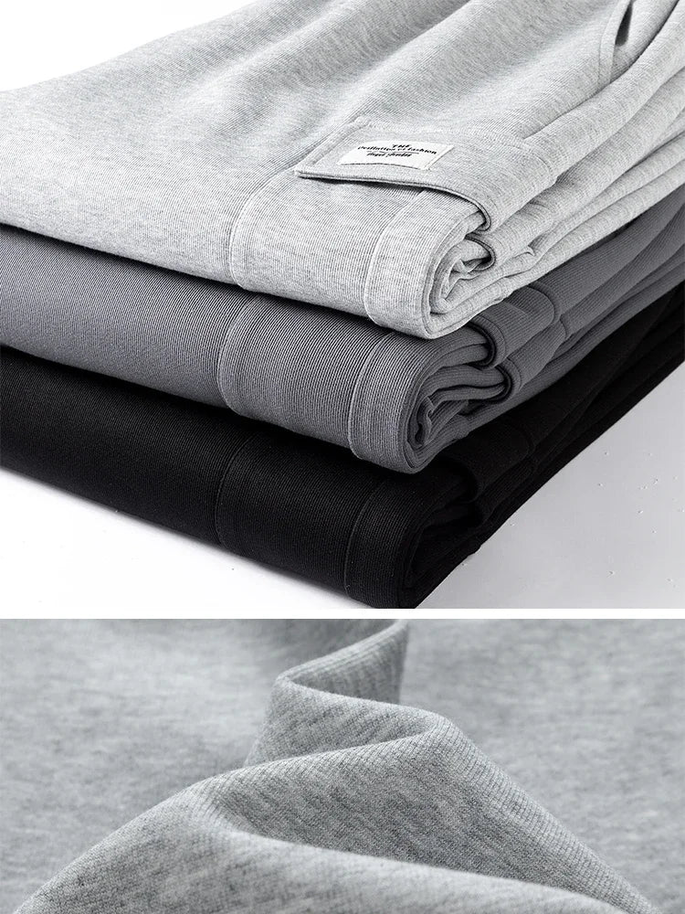 A collage image showing Urban Nomad cargo sweatpants. The top panel displays a stack of folded cargo sweatpants in light gray, dark gray, and black, highlighting the different color variants and a small label on the light gray pair. The bottom panel features a close-up shot of the soft cotton fabric texture of the light gray sweatpants.