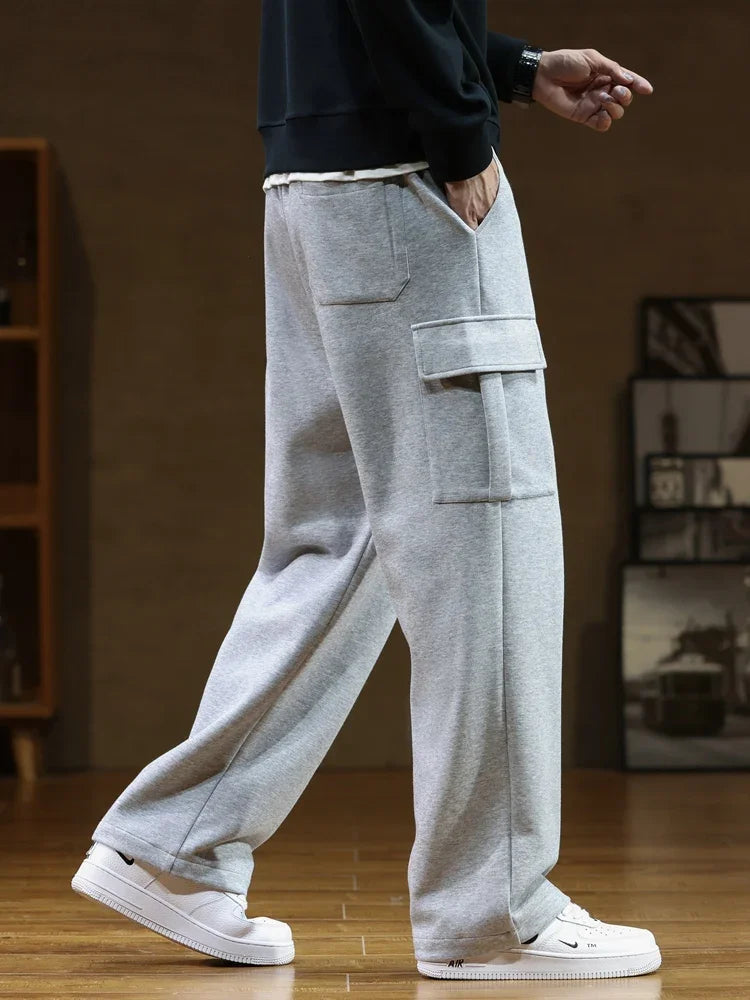 Urban Nomad light gray cargo sweatpants made from soft cotton, featuring a relaxed fit and a large utility pocket on the side. Worn by a person walking, showcasing the side profile.
