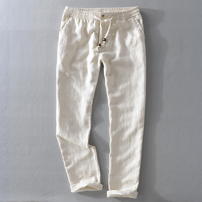 Beige Willow Grove casual linen pants with a relaxed fit, shown in a flat lay, front view. The pants feature an elastic waistband with a natural rope drawstring and wooden beads, and the hems are cuffed.
